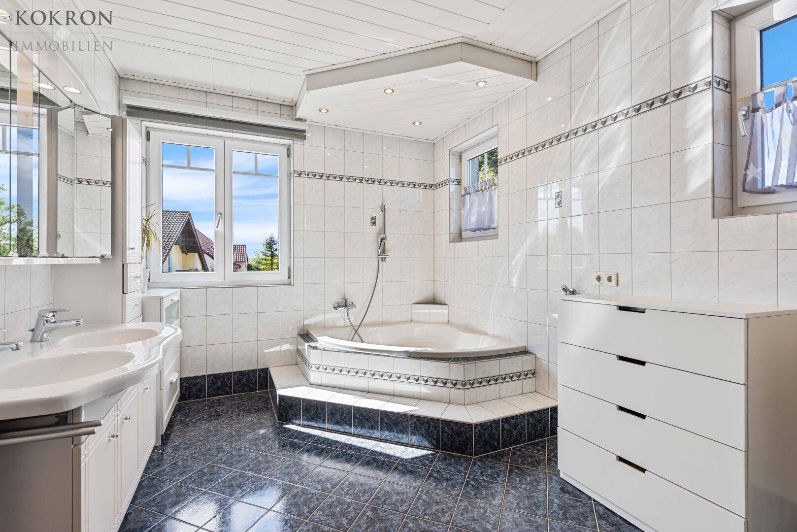 Geräumiges Badezimmer mit Eckbadewanne, Doppelwaschbecken und Fenster für natürliche Belüftung.