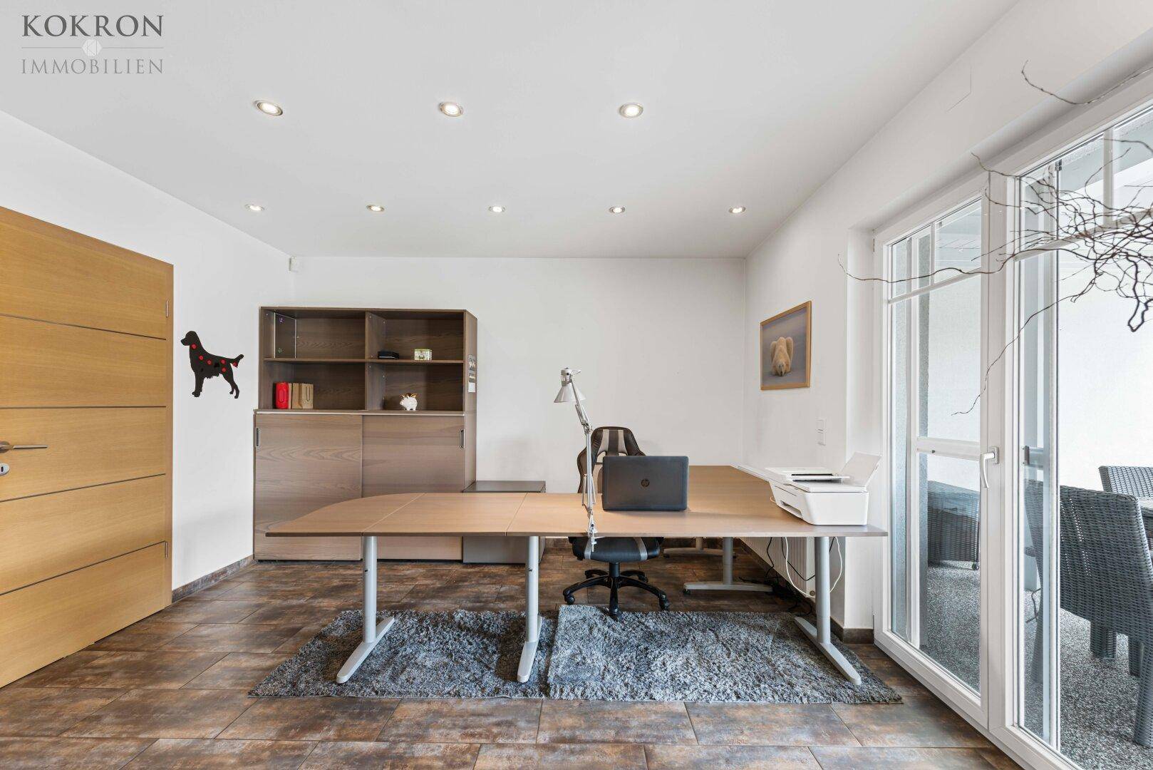 Helles Arbeitszimmer mit großem Schreibtisch und Zugang zu einer Terrasse oder einem Balkon.