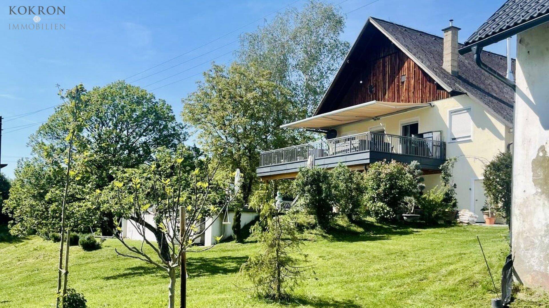 Großer Balkon mit Markise und Sitzgelegenheiten, der einen weiten Blick über die grüne Landschaft bietet.