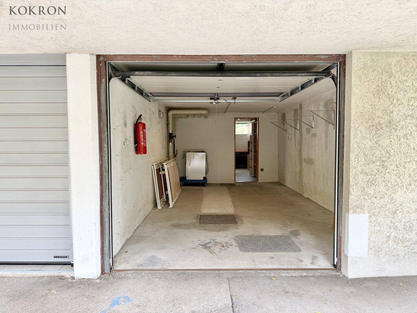 Leere Garage mit Betonboden und Rolltor, bietet Platz für ein Fahrzeug und Lagerung.