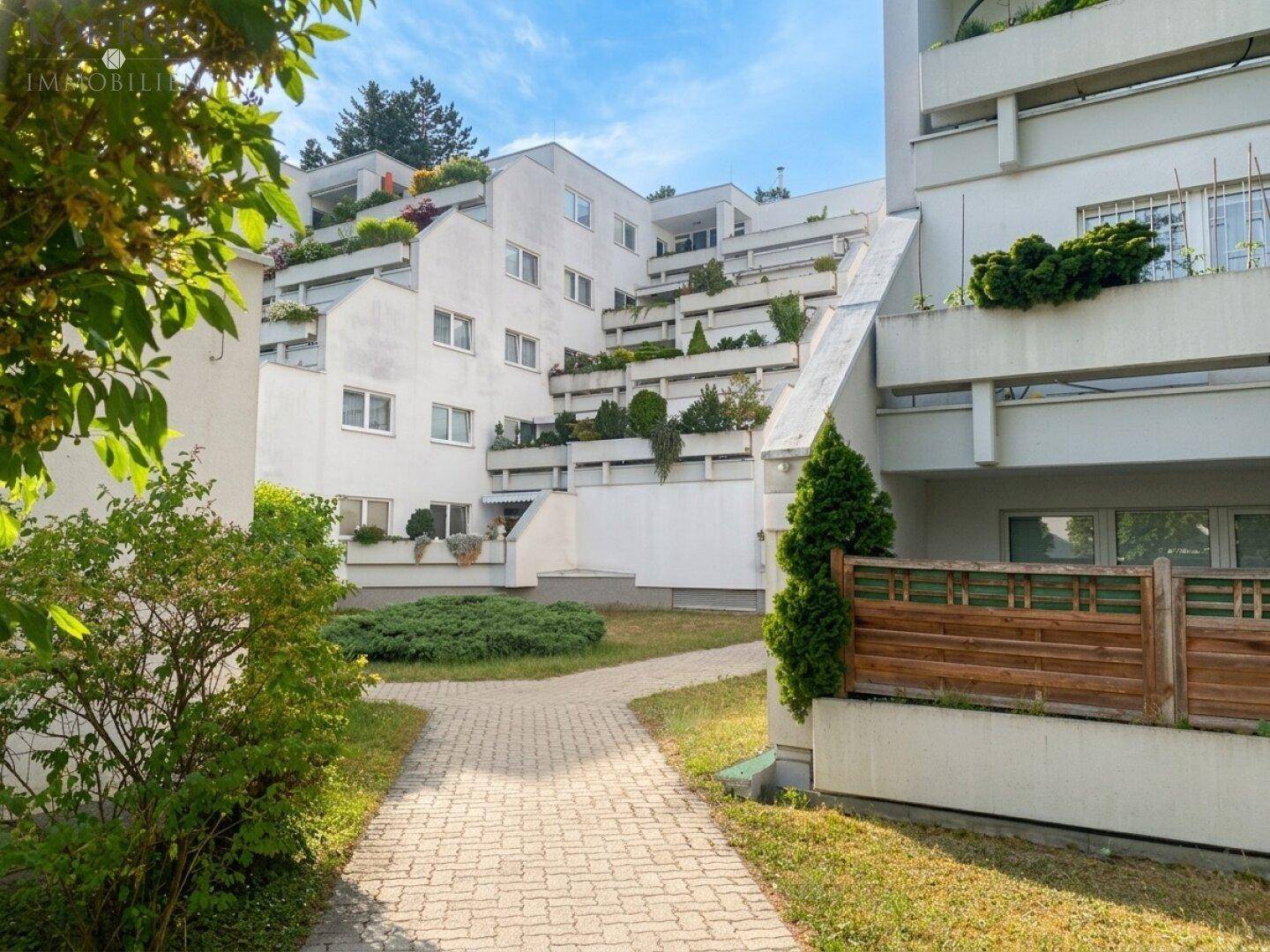 Terrassenförmig angelegte Wohnanlage mit viel Grün und Wegen, eingebettet in die Natur.