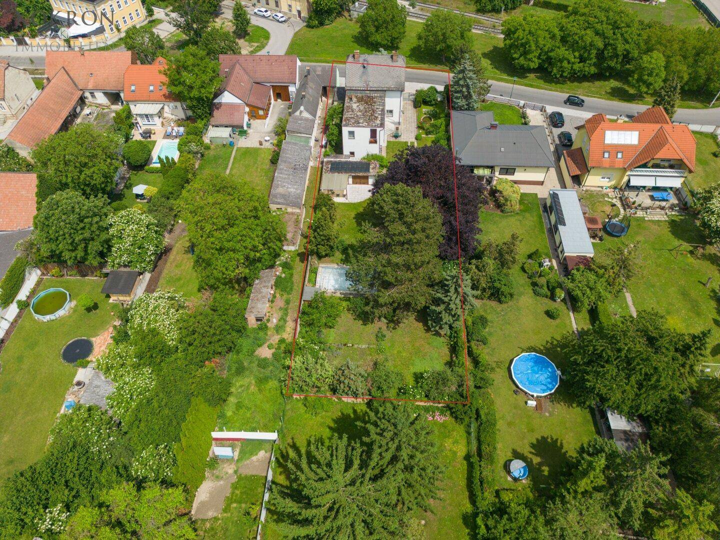 Übersicht des Grundstücks aus der Vogelperspektive mit angrenzenden Gärten und einem Pool.