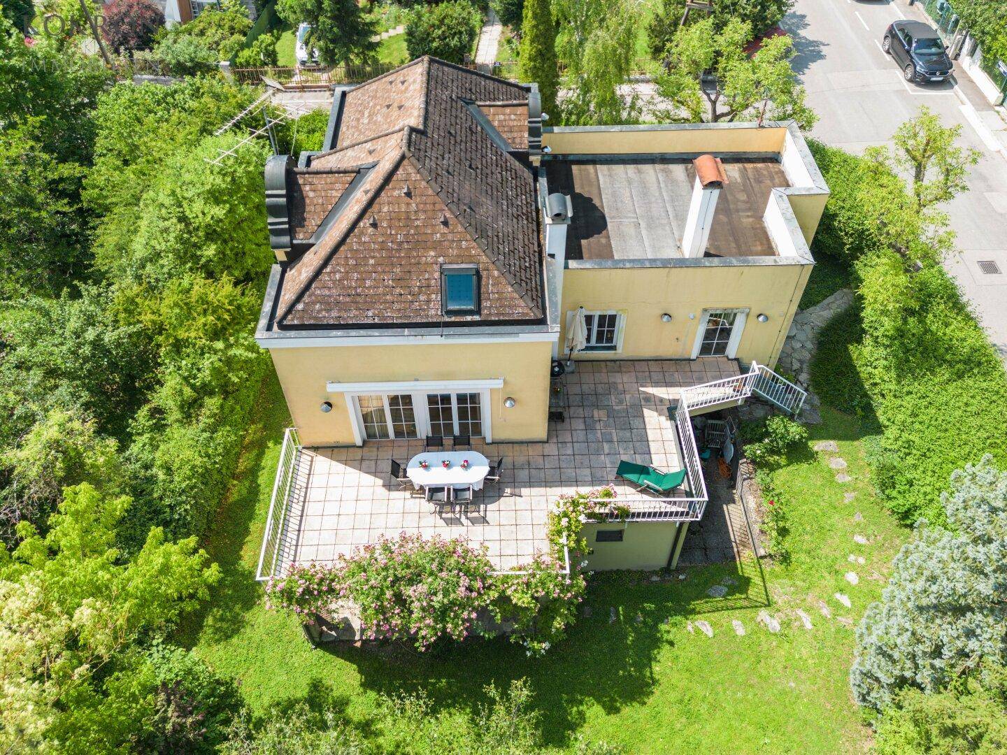 Vogelperspektive des Hauses mit großer gefliester Terrasse und umgebendem Gartenbereich.