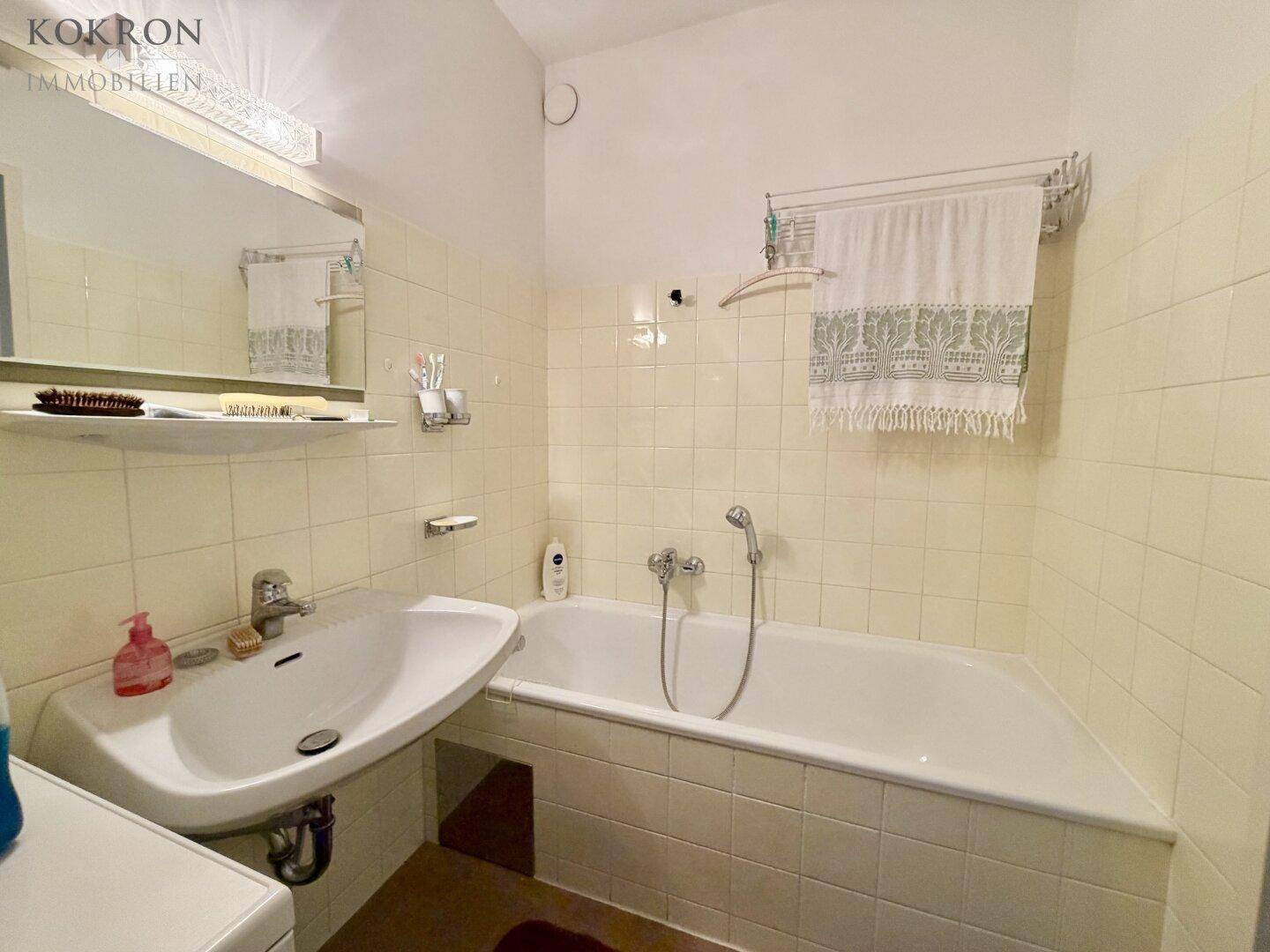 Badezimmer mit Badewanne, Waschbecken und gelben Fliesen, funktional eingerichtet.