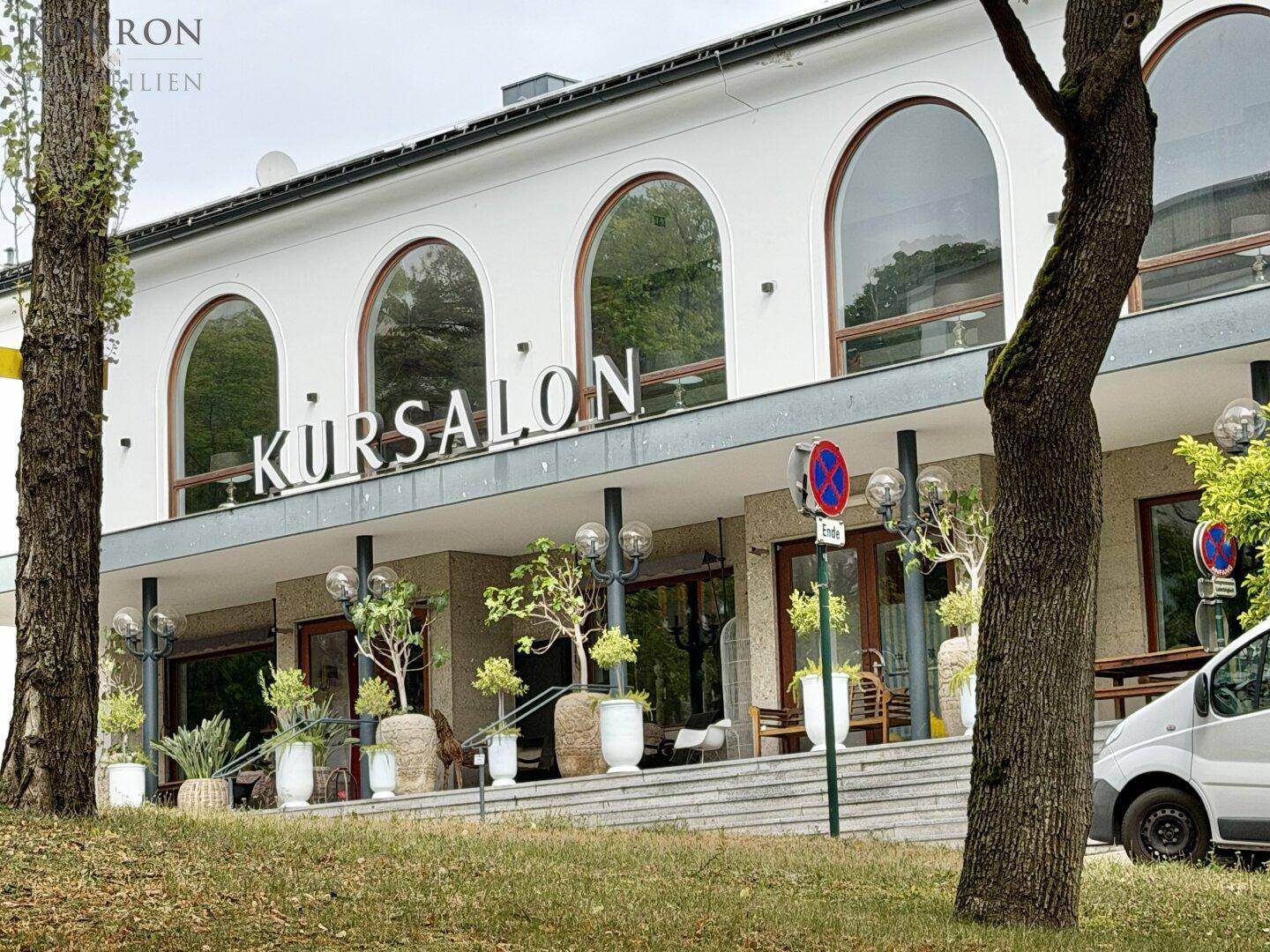 Historisches Gebäude 'Kursalon' mit großen Rundbogenfenstern und dekorativen Pflanzen im Eingangsbereich.