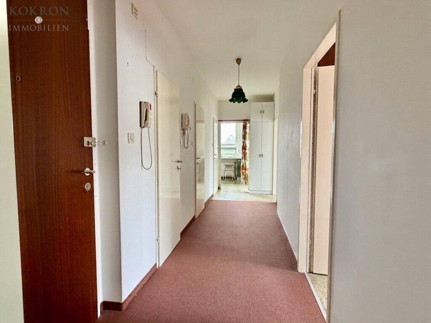 Langer Flur mit Teppichboden und mehreren Türen, der zu weiteren Räumen führt.