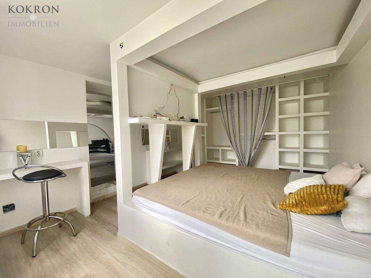 Schlafzimmer mit integriertem Bettrahmen und Regalen, heller Laminatboden und moderne Gestaltungselemente.