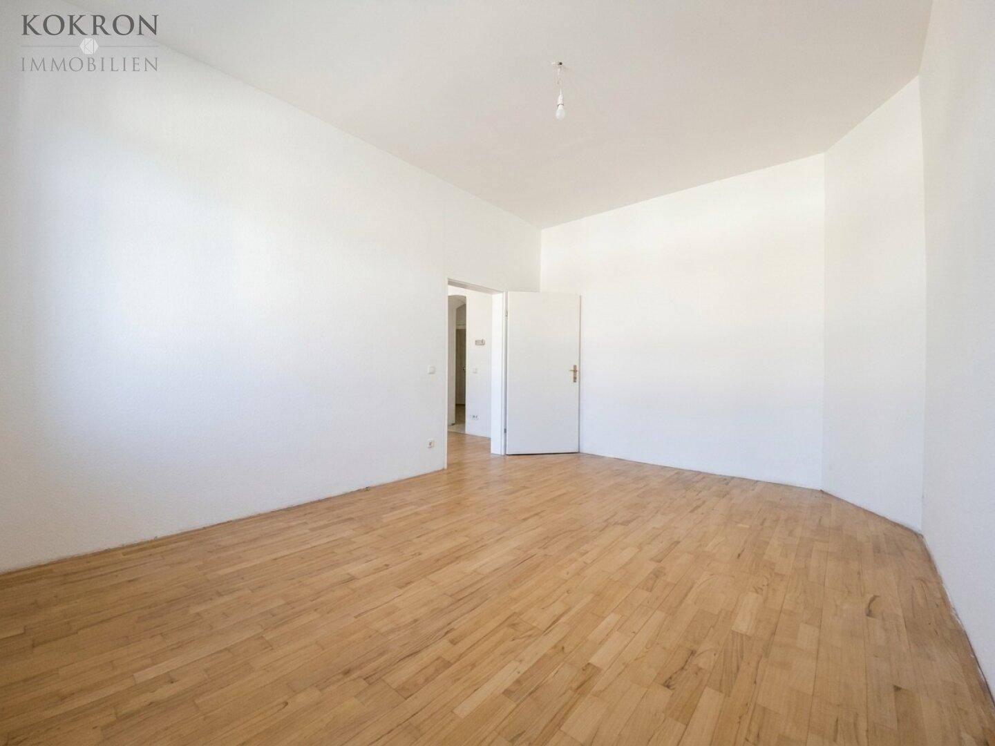 Leeres Zimmer mit hellem Holzboden und weiß gestrichenen Wänden, bereit zur individuellen Gestaltung.