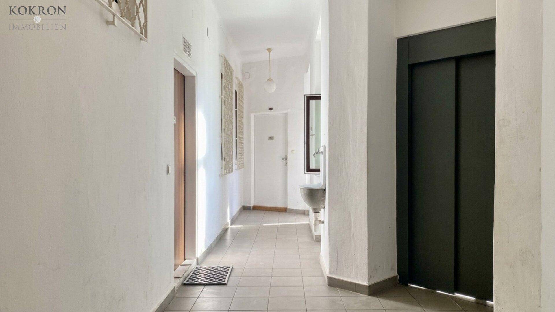 Heller Hausflur mit Fliesenboden, einem Waschbecken und einem modernen Aufzug für bequemen Zugang.