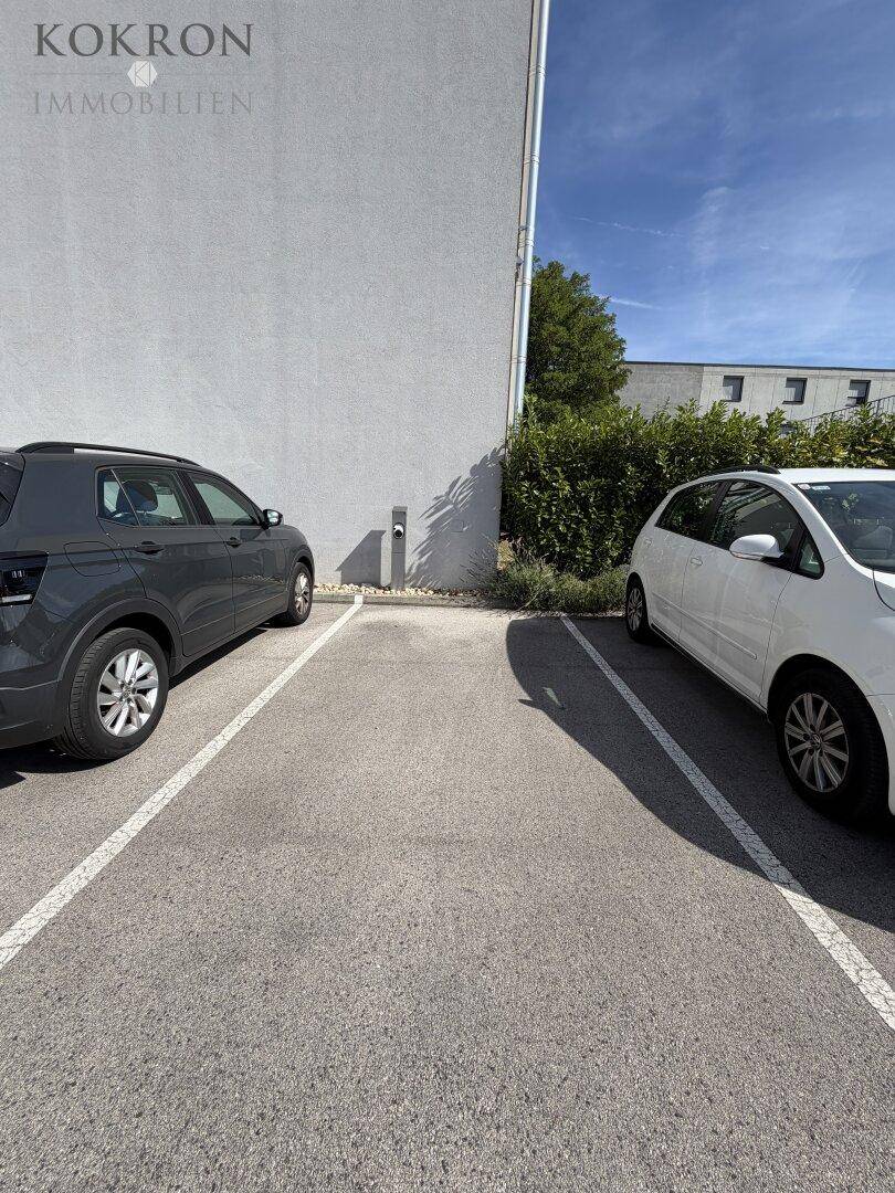 Außenparkplätze vor dem Gebäude mit einer Ladestation für Elektrofahrzeuge.