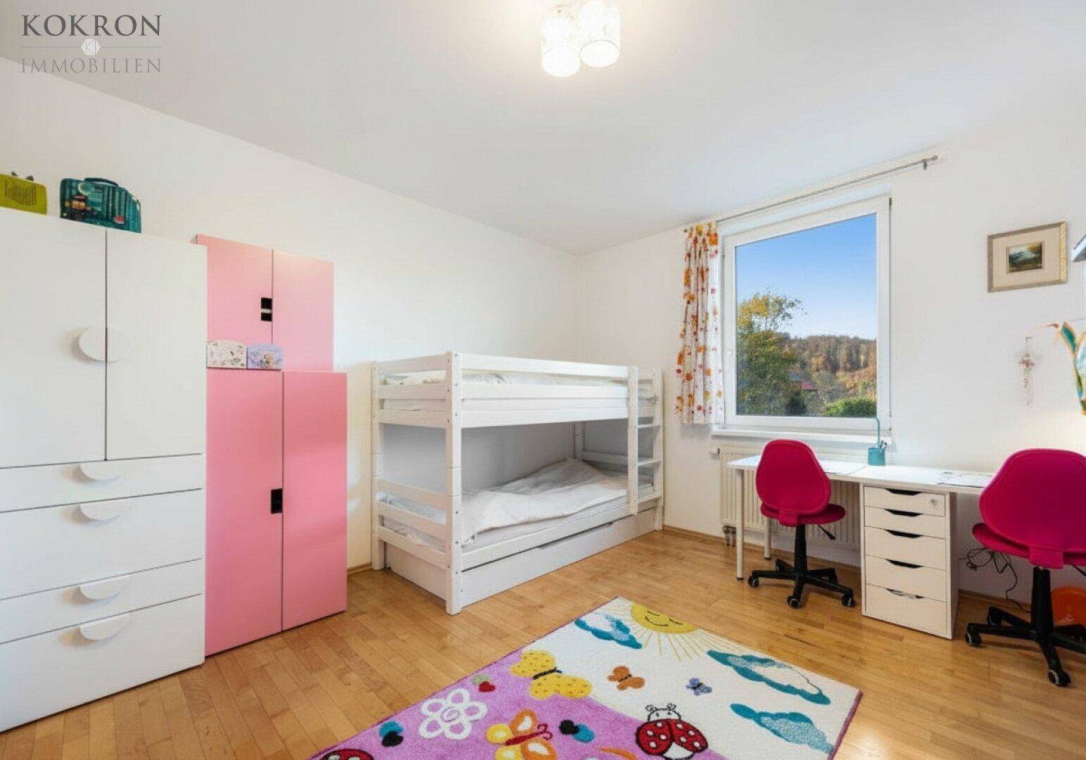 Kinderzimmer mit Etagenbett, Schreibtischen und farbenfrohem Teppich, ideal für Geschwister.