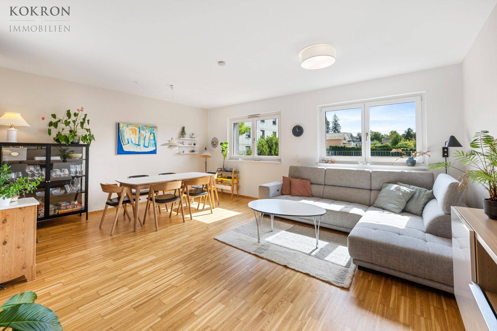 Helles und geräumiges Wohn-Esszimmer mit Parkettboden, großem Sofa und Esstisch, ideal für Familienleben.