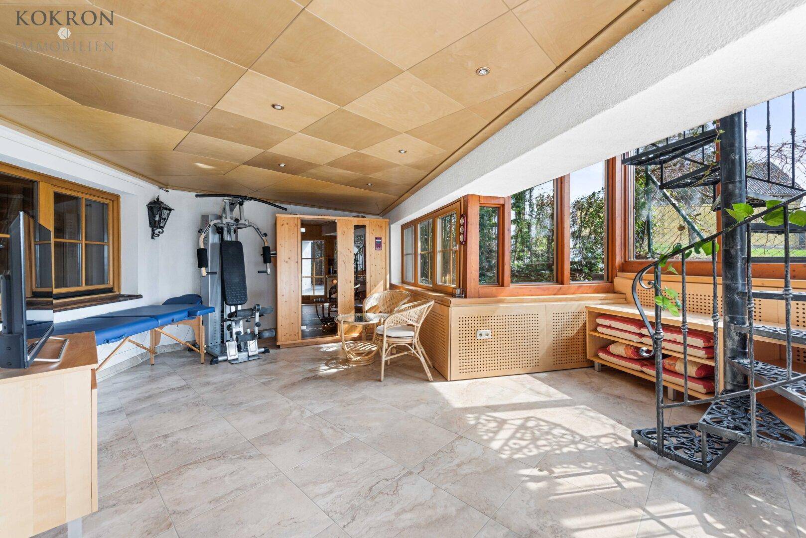 Geräumiger Wellnessbereich mit Sauna, Fitnessgeräten und Wendeltreppe, hell und einladend gestaltet.