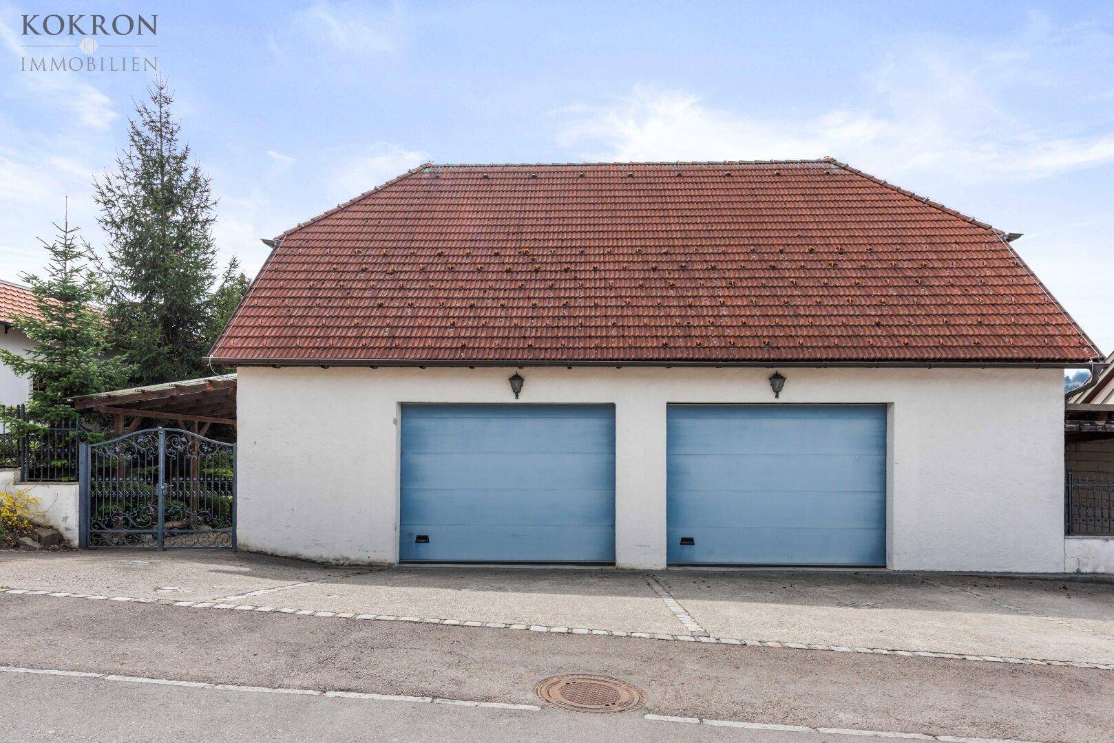 Doppelgarage mit blauen Toren und Satteldach, an einer ruhigen Straße gelegen und gut gepflegt.