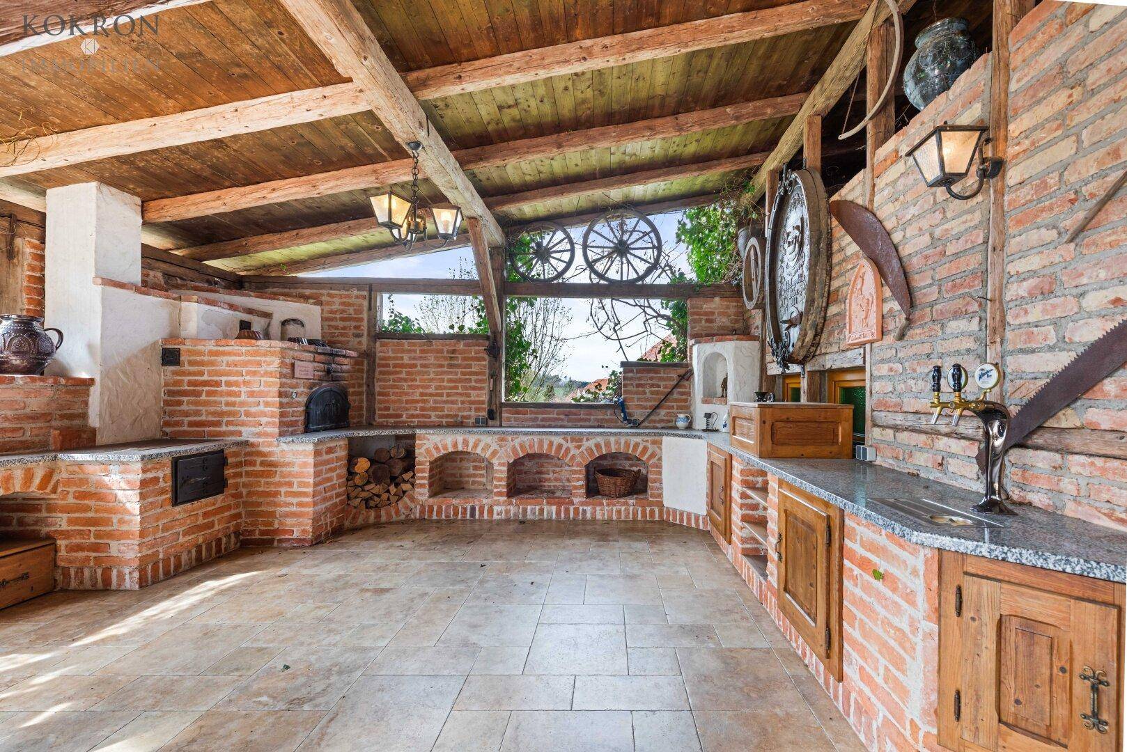 Rustikale Außenküche mit Grillbereich, Ziegelmauern und Holzbalkendecke, ideal für gesellige Abende.