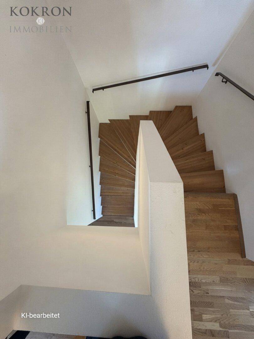 Moderne Holztreppe mit schlichtem Geländer, die die verschiedenen Ebenen des Hauses elegant verbindet.