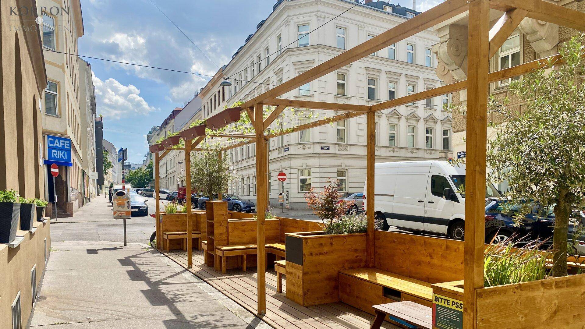 Belebte Stadtstraße mit einem charmanten Café und gemütlichen Sitzgelegenheiten im Freien.