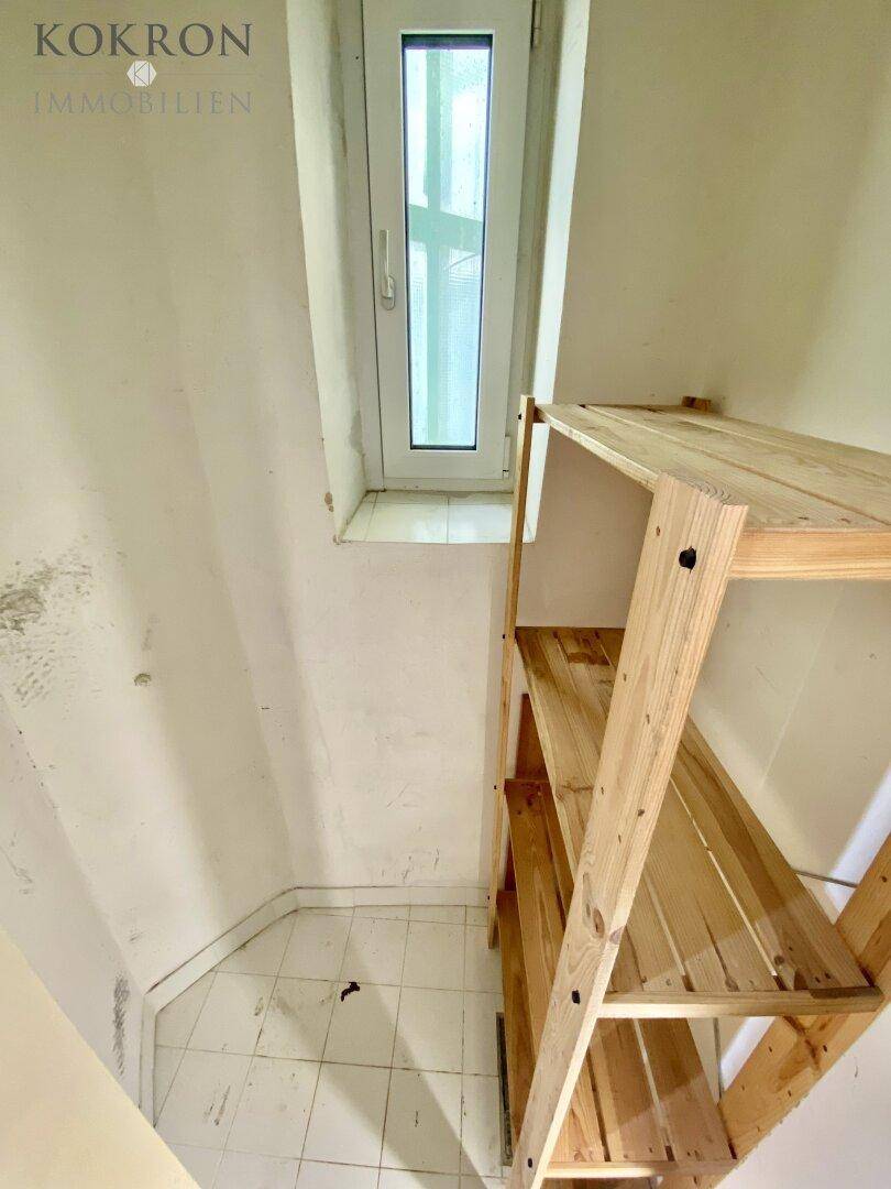 Kleiner Abstellraum mit Holzregalen und einem schmalen Fenster, ideal für zusätzlichen Stauraum.