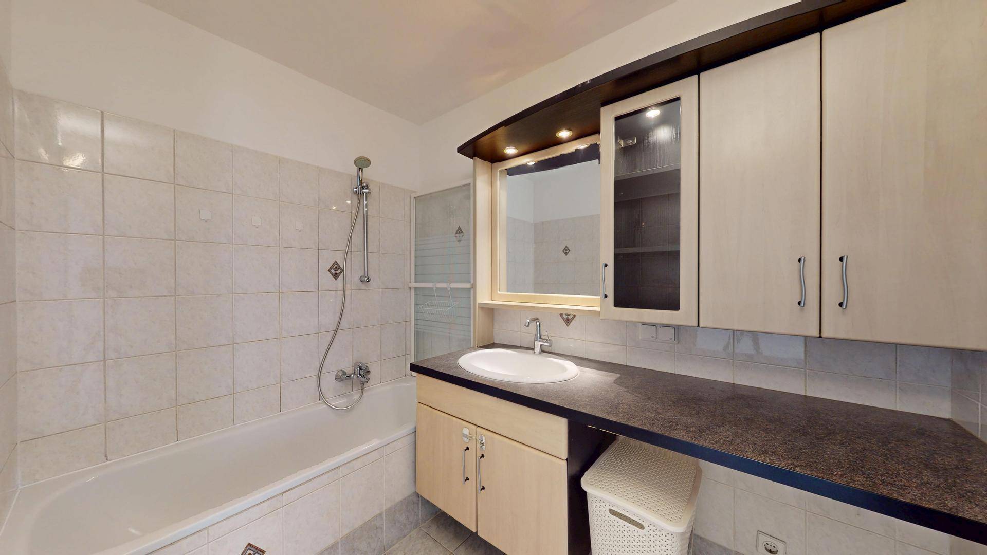 Badezimmer mit Badewanne, Waschbecken und Spiegelschrank über dem Waschtisch.