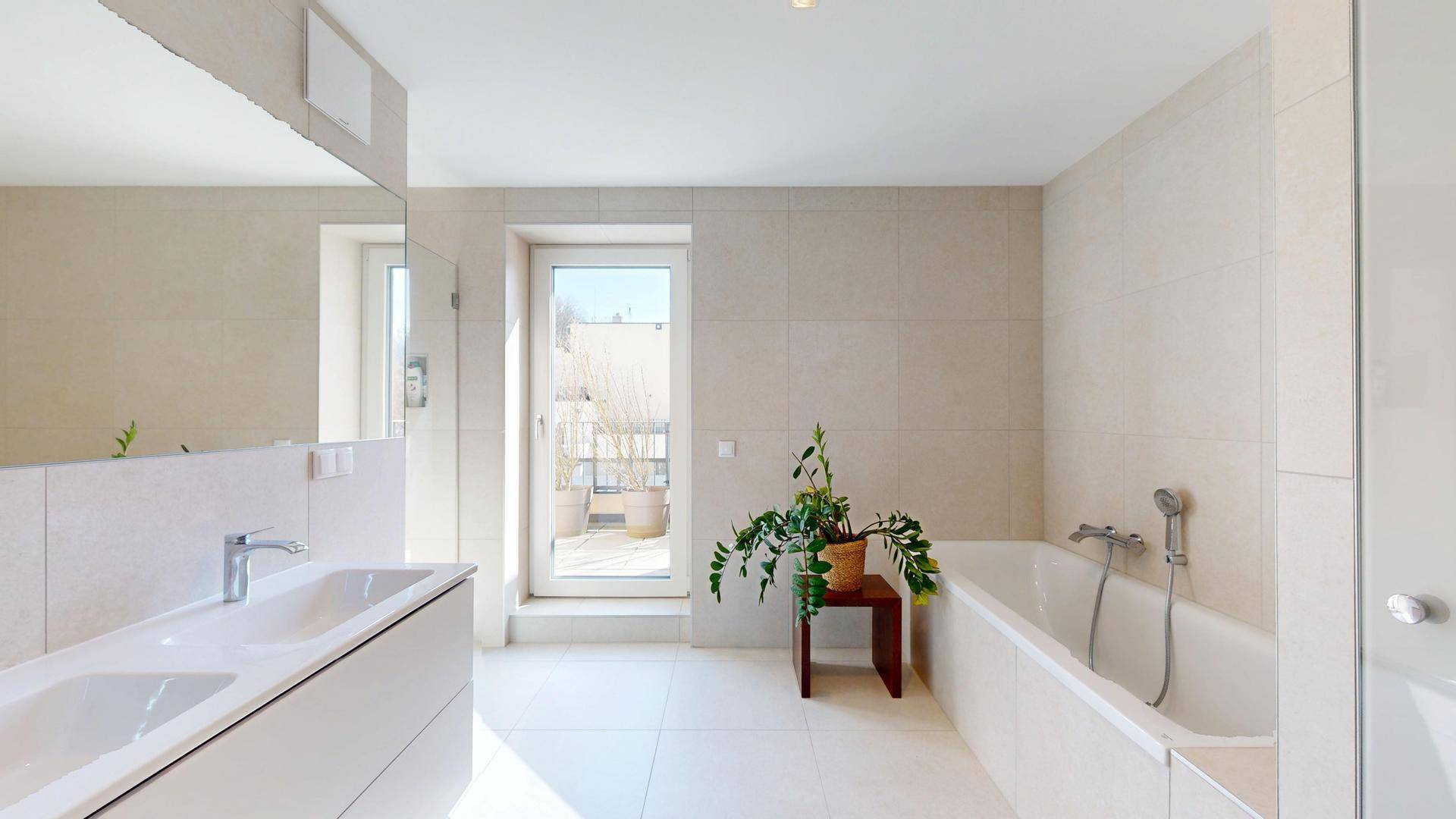 Modernes Badezimmer mit Doppelwaschbecken, Badewanne und Zugang zur Terrasse.