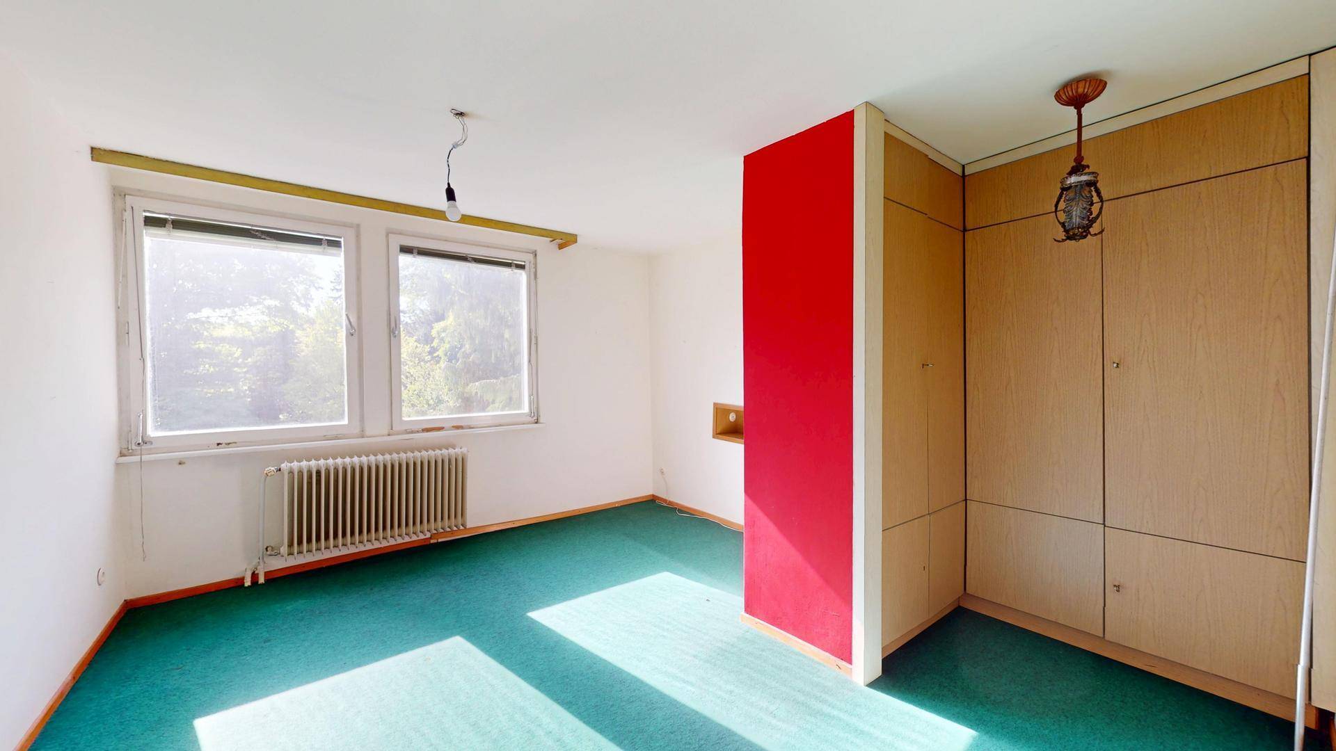 Helles Zimmer mit Teppichboden, Einbauschränken und farbiger Wand, bietet vielseitige Nutzungsmöglichkeiten.