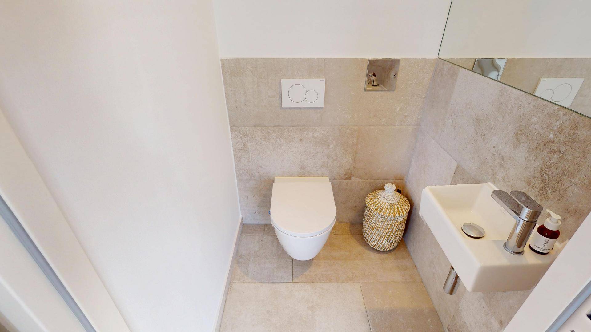 Kleines Gäste-WC mit wandhängendem WC, modernem Waschbecken und hellen Fliesen.