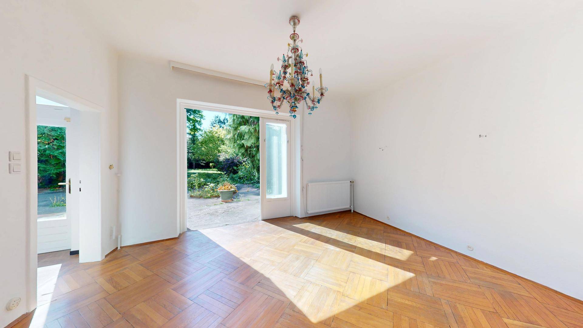 Leerer Essbereich mit Parkettboden und direktem Zugang zum Garten, der viel Tageslicht hereinlässt.