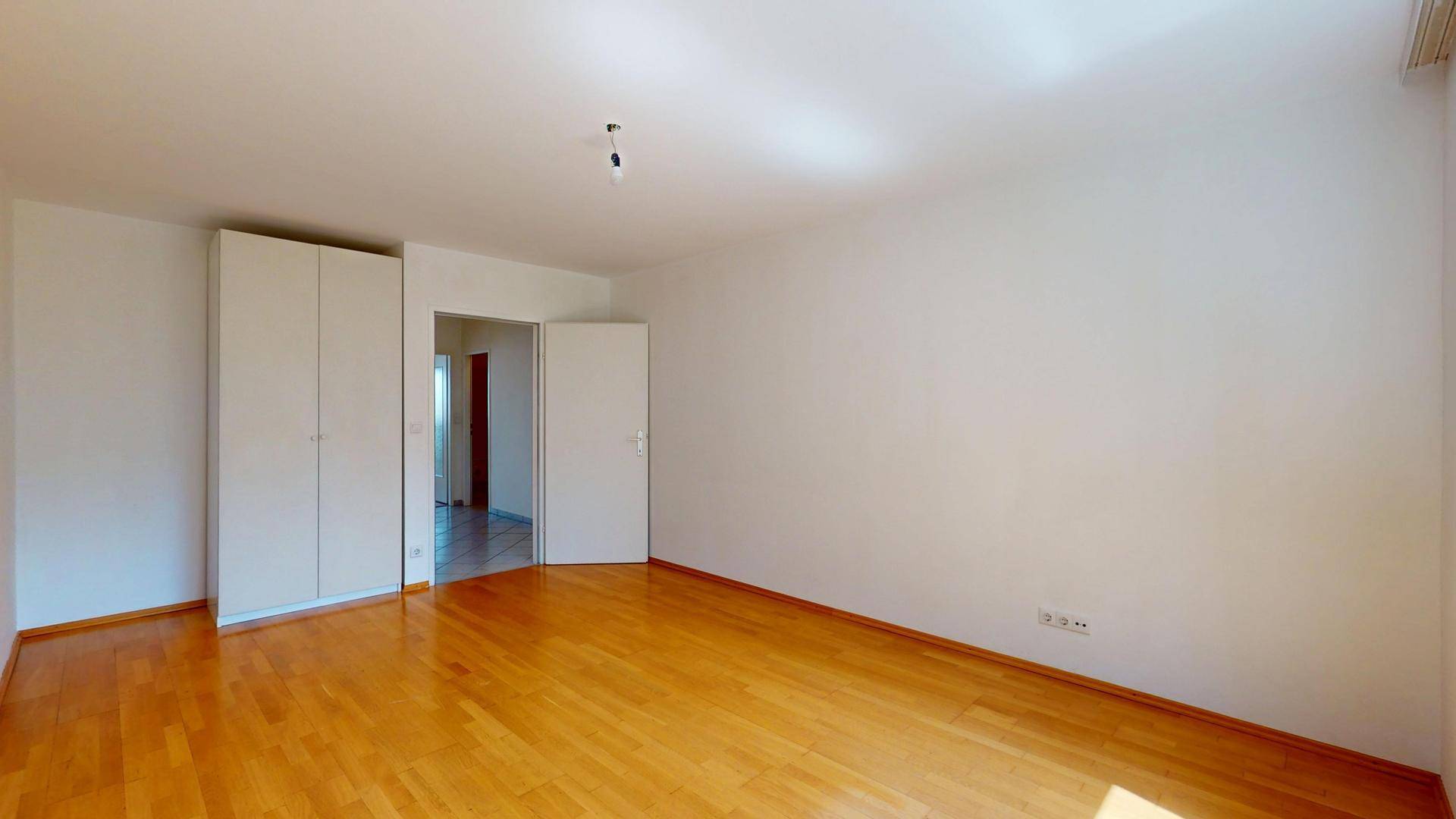Geräumiges Schlafzimmer mit Parkettboden und praktischen Einbauschränken.
