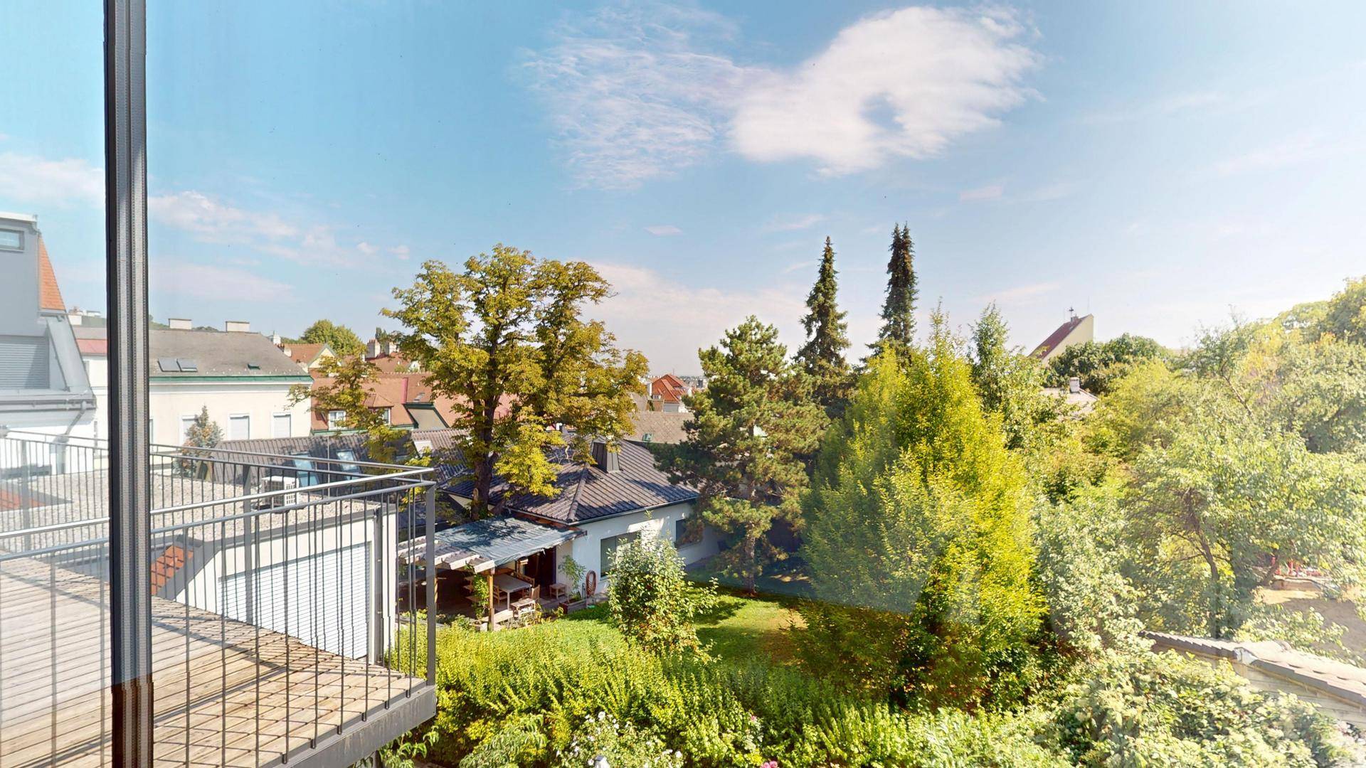 Panoramablick vom Balkon über grüne Gärten und die umliegende Wohngegend an einem sonnigen Tag.