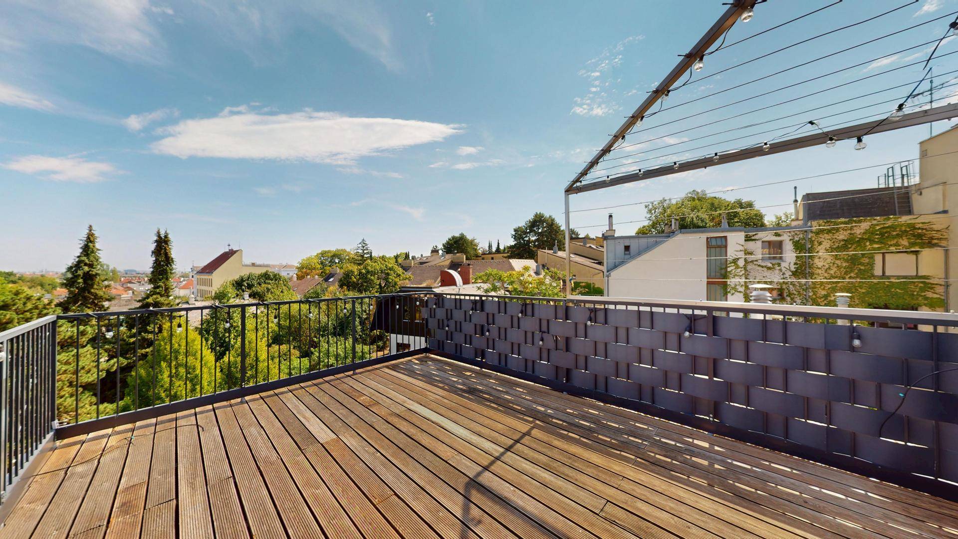 Sonnige Dachterrasse mit Holzboden und dekorativer Beleuchtung, perfekt für Abendstunden.