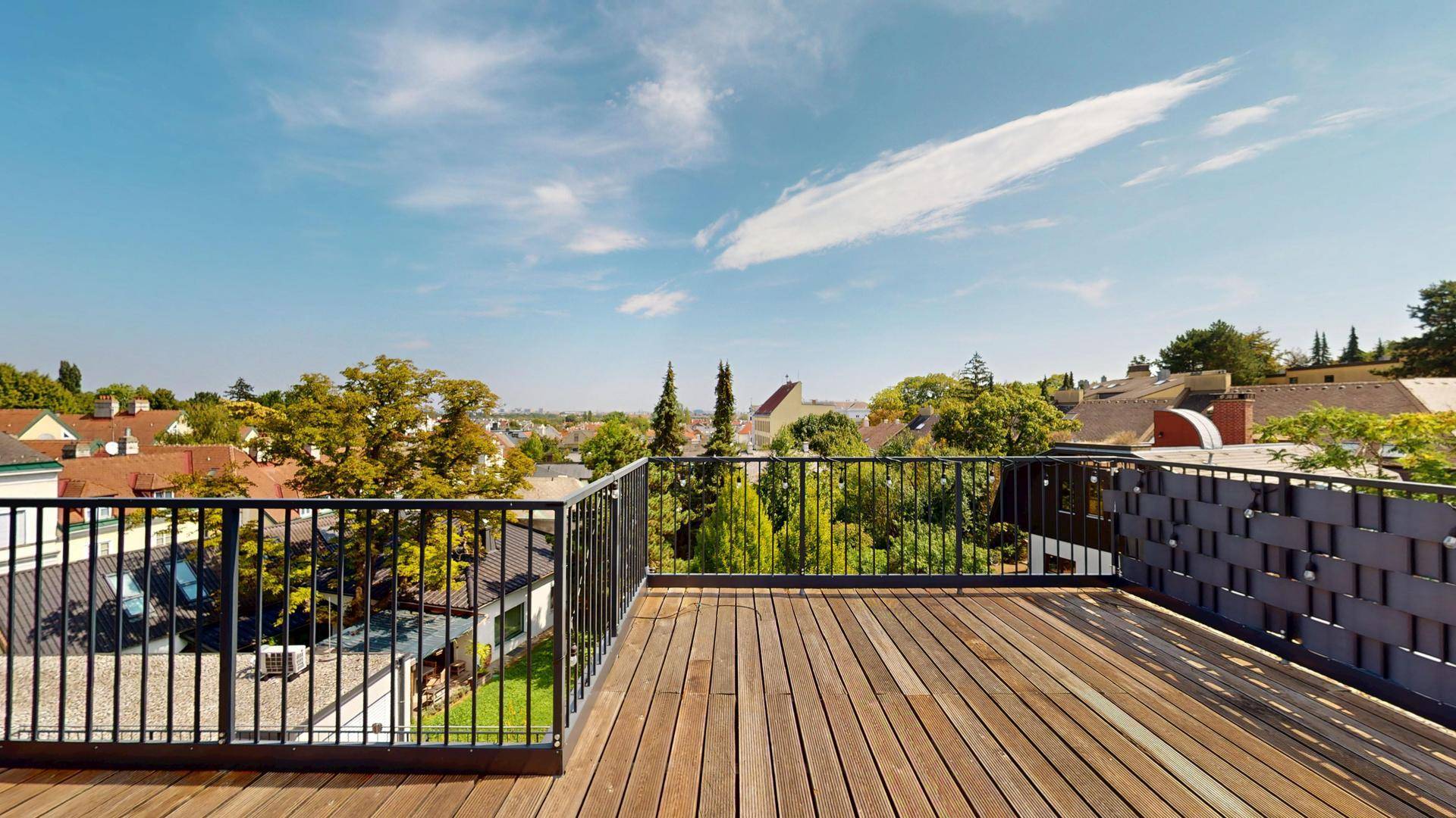 Weitläufige Dachterrasse mit Holzdielen und modernem Geländer, ideal für Entspannung im Freien.
