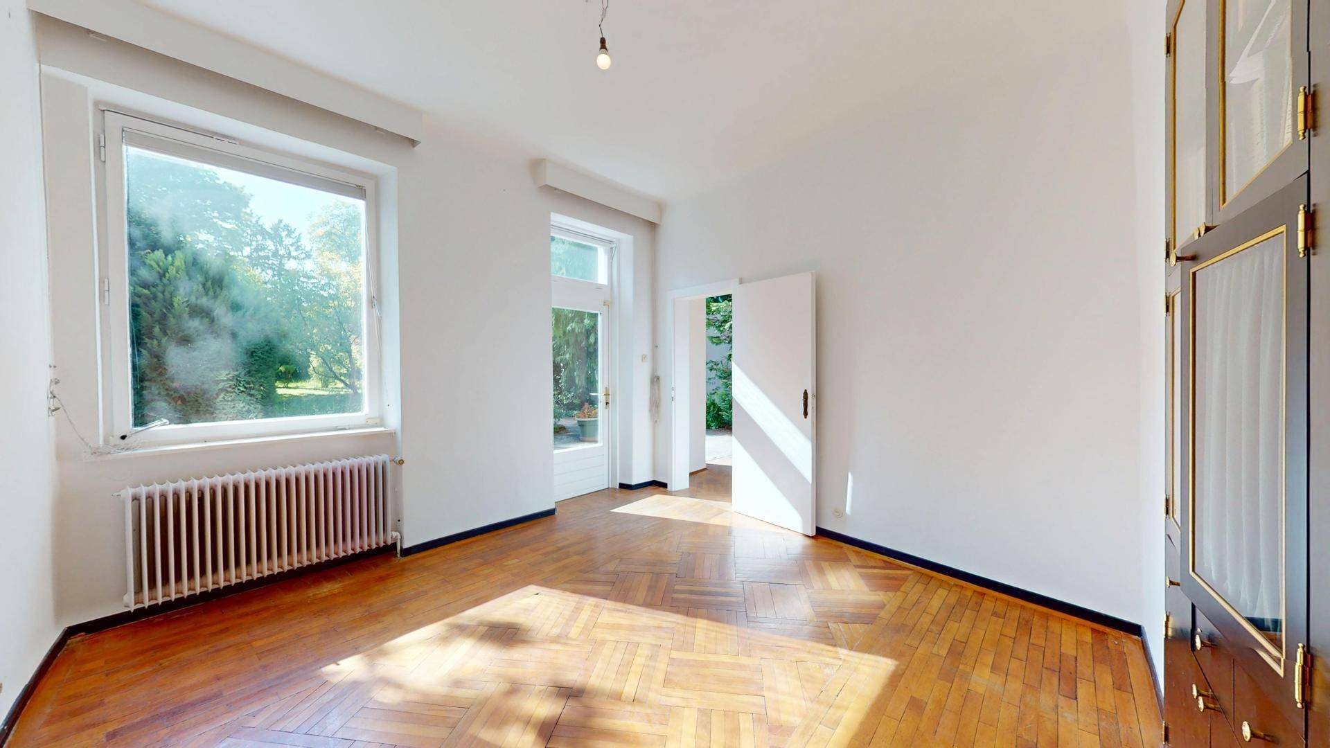 Helles Zimmer mit Parkettboden und großen Fenstern zum Garten, vielseitig nutzbar als Büro oder Schlafzimmer.