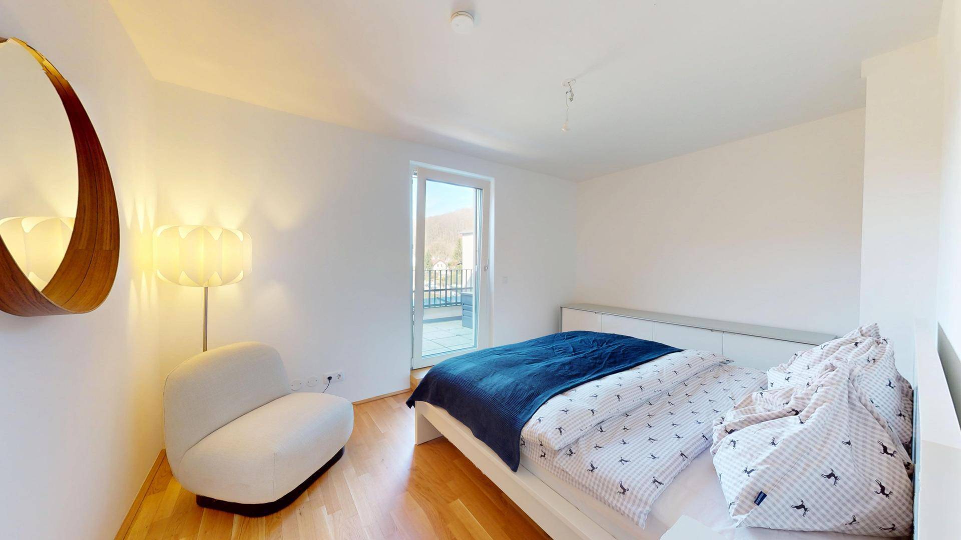 Helles Schlafzimmer mit Holzboden, modernem Bett und Zugang zu einem Balkon.