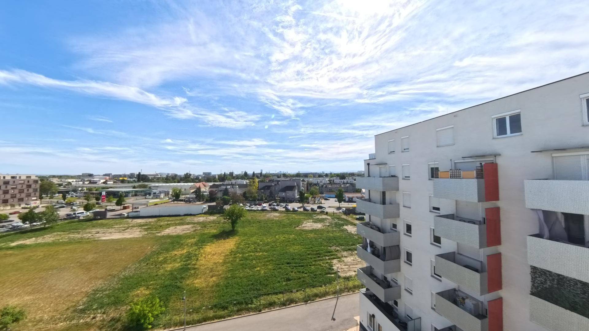 Panoramablick über die Umgebung mit Wohngebäuden, weiten Grünflächen und städtischen Elementen.