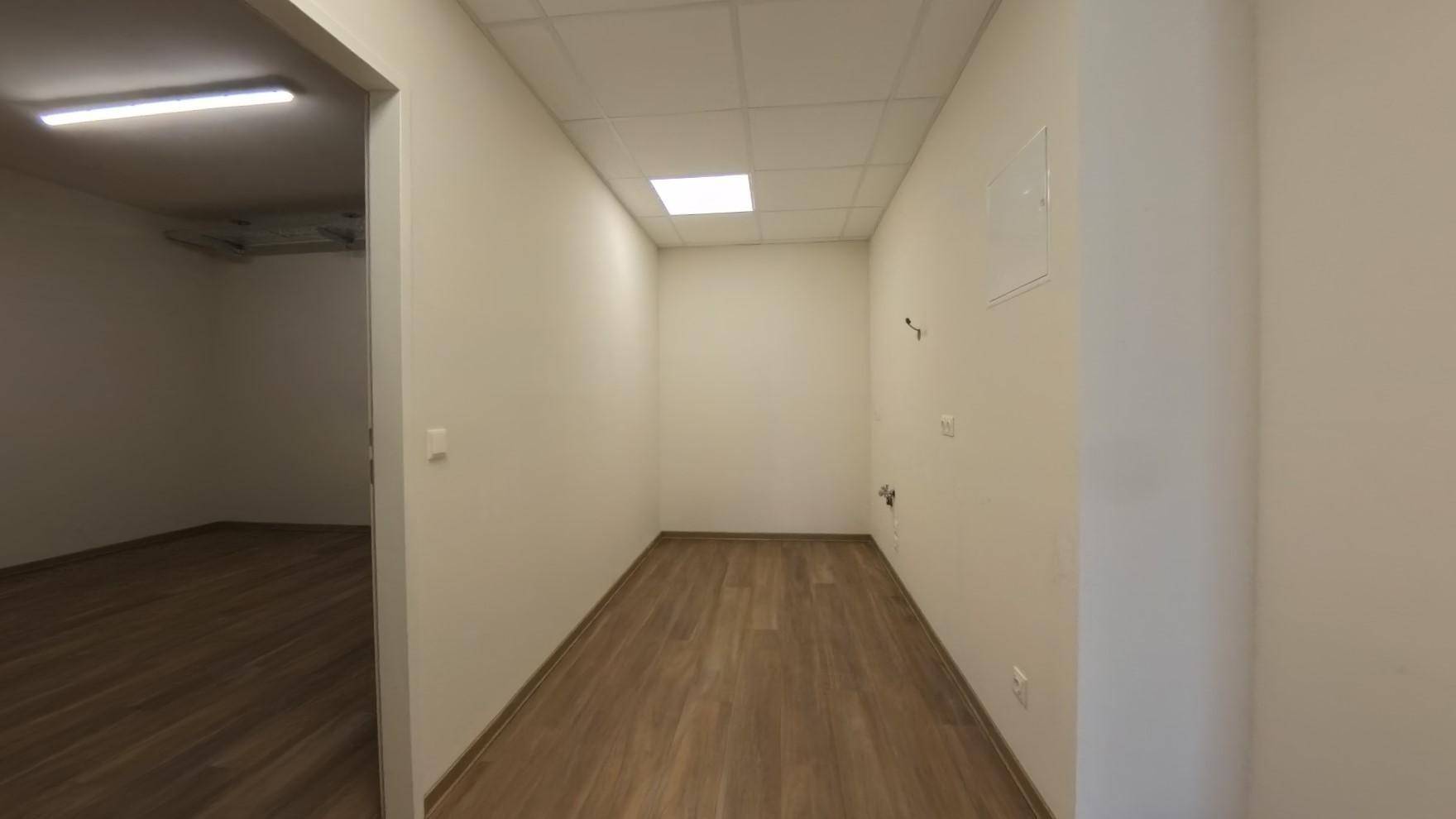 Schmaler Flur mit Laminatboden und einer Deckenbeleuchtung, der zu weiteren Räumen führt.