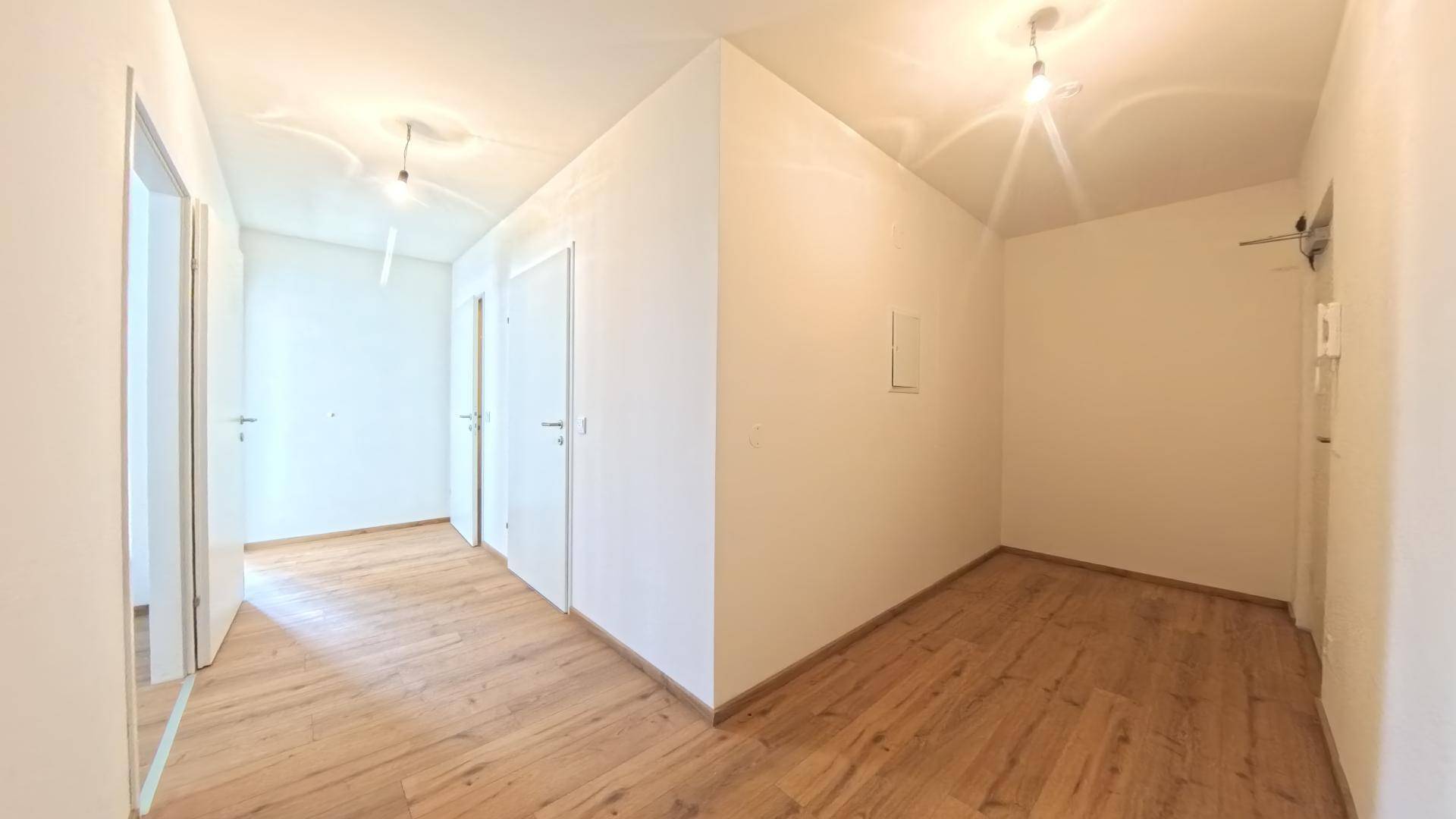 Heller Flur mit Laminatboden, der zu verschiedenen Zimmern und dem Eingangsbereich führt.