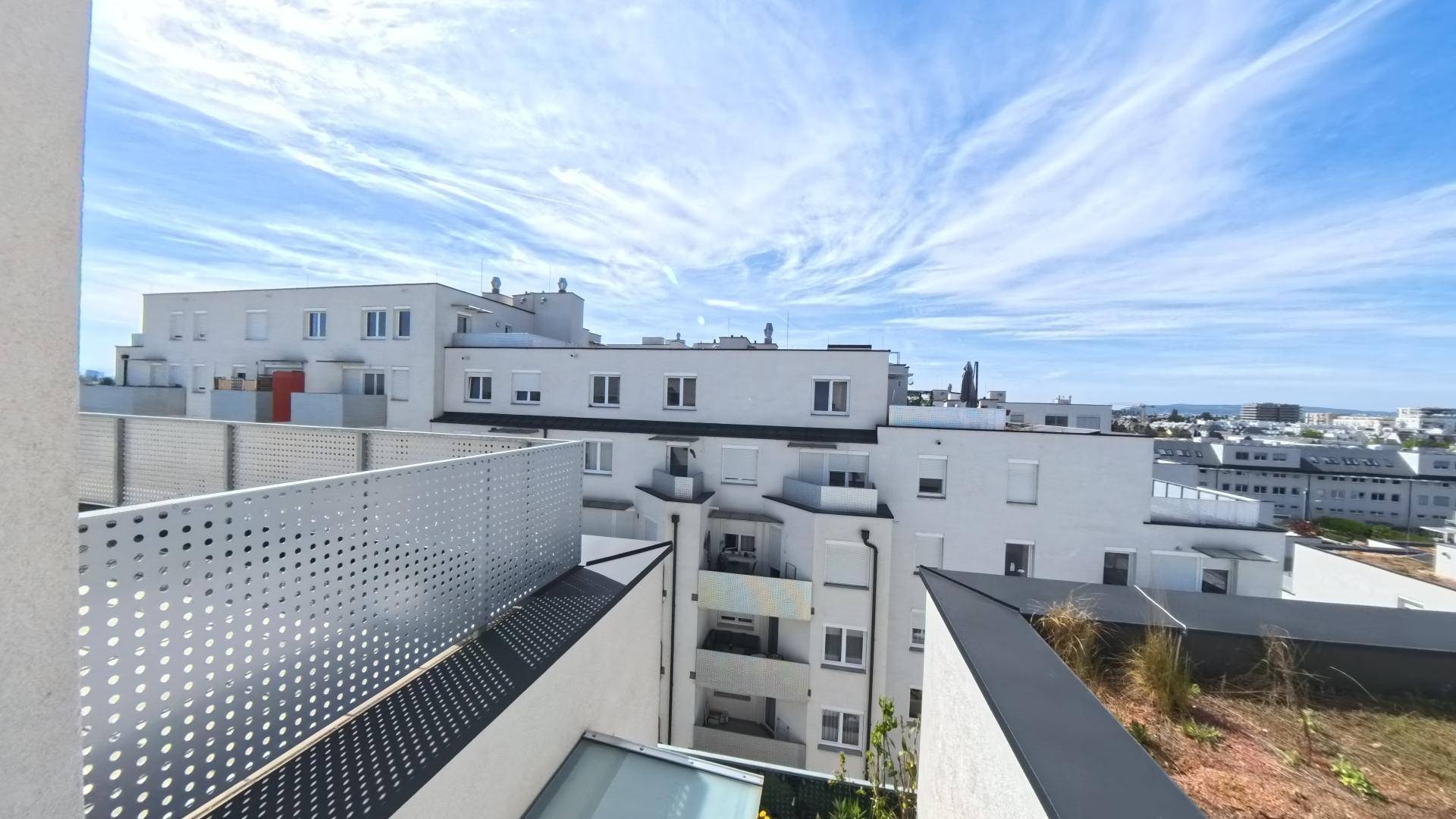 Weitläufiger Blick von der Dachterrasse über die umliegenden Wohngebäude und den Himmel.