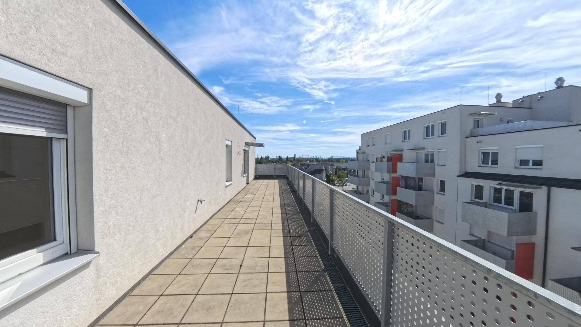 Geräumige Dachterrasse mit Fliesenbelag und Blick auf die umliegenden Wohngebäude.