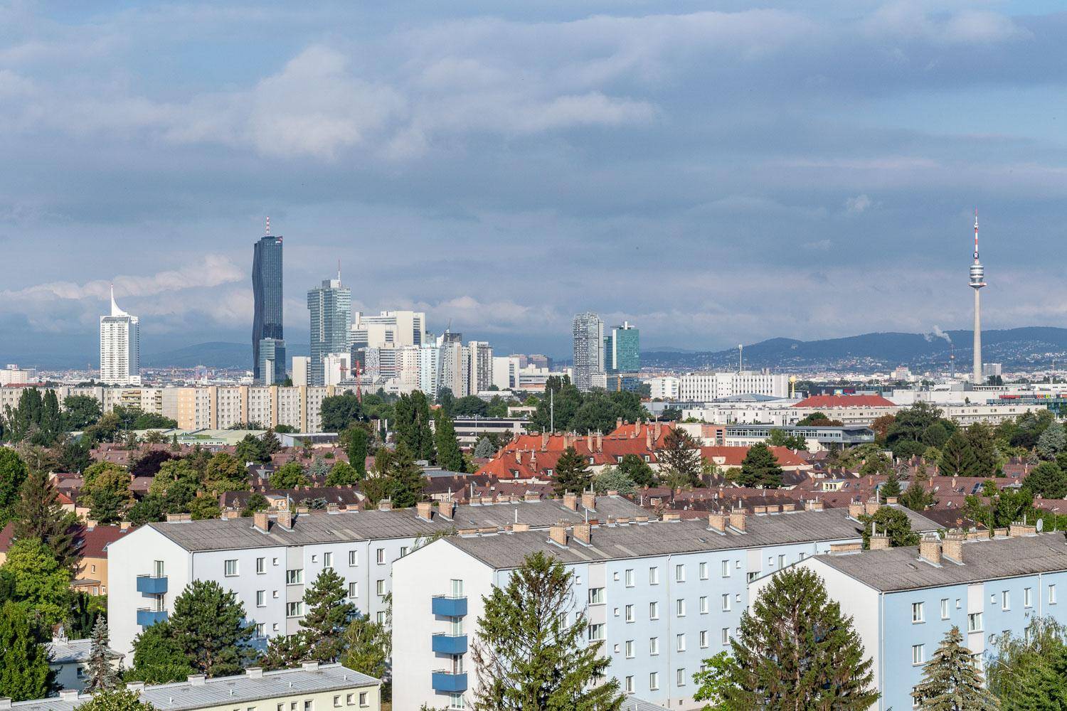 Panoramablick auf die Skyline einer modernen Stadt mit Hochhäusern und Wohngebäuden im Vordergrund.