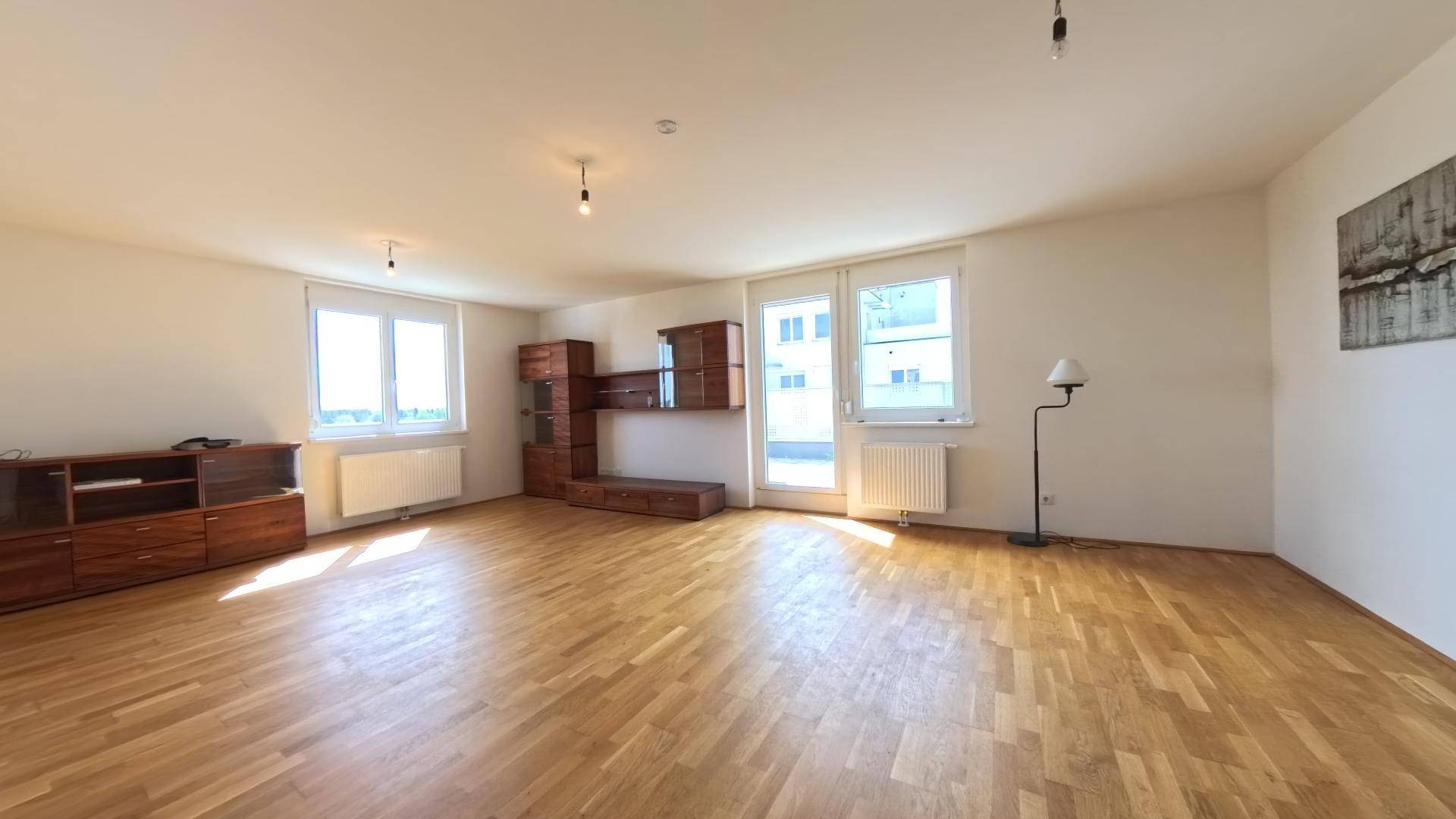 Lichtdurchflutetes Wohnzimmer mit Eichenparkett und Zugang zu einem sonnigen Außenbereich.