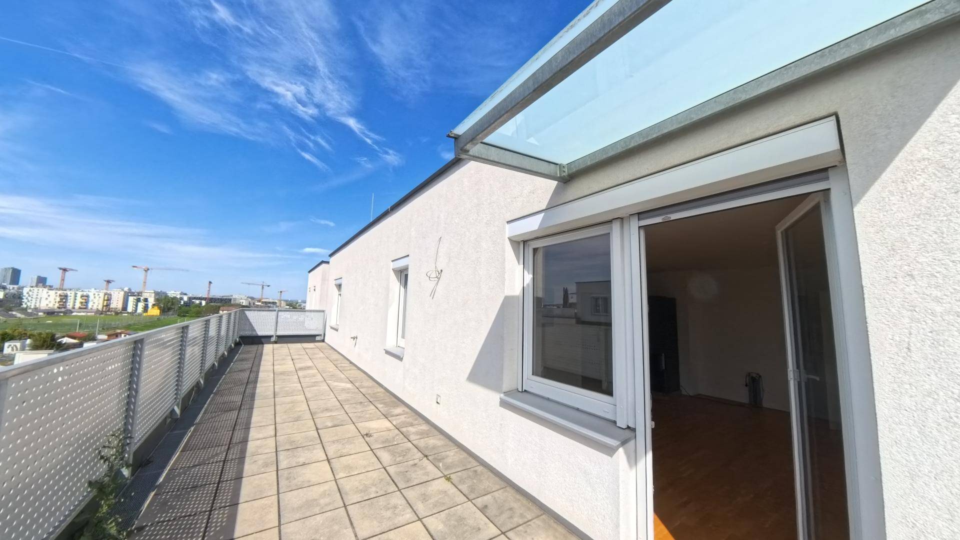 Sonniger Terrassenbereich mit Fliesenboden und Zugang zum Innenraum, ideal für Entspannung.
