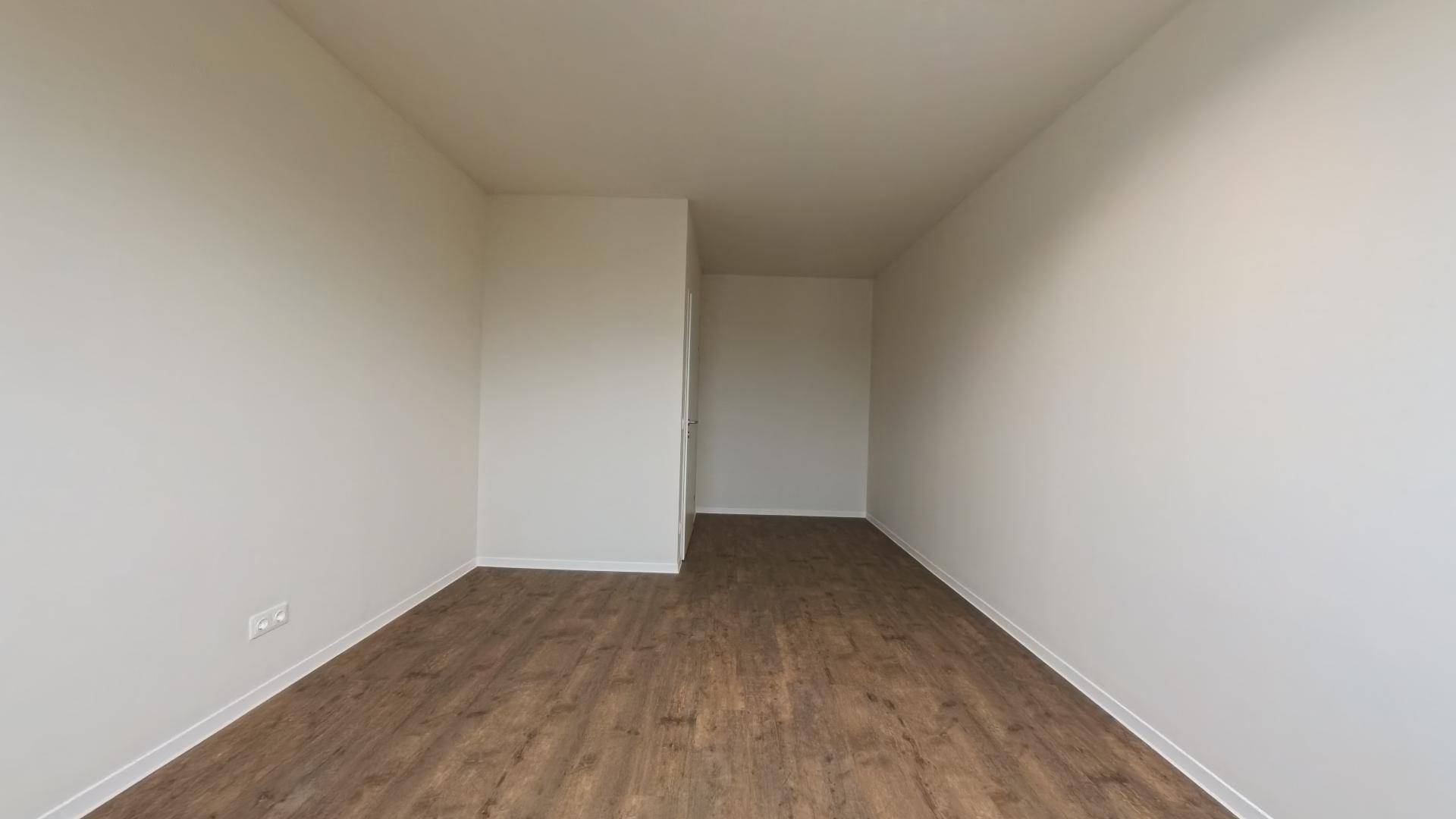 Leeres, helles Büro mit Holzboden und weißen Wänden, bereit für neue Mieter.