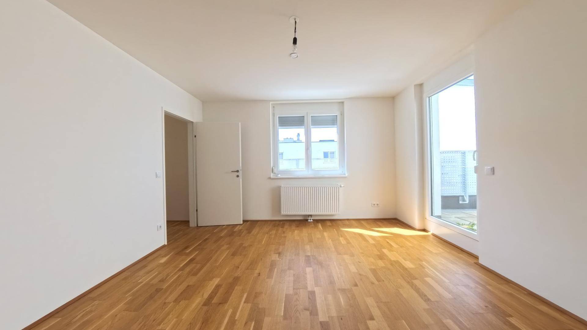 Geräumiges Schlafzimmer mit Parkettboden, Fenster und Zugang zum Außenbereich.