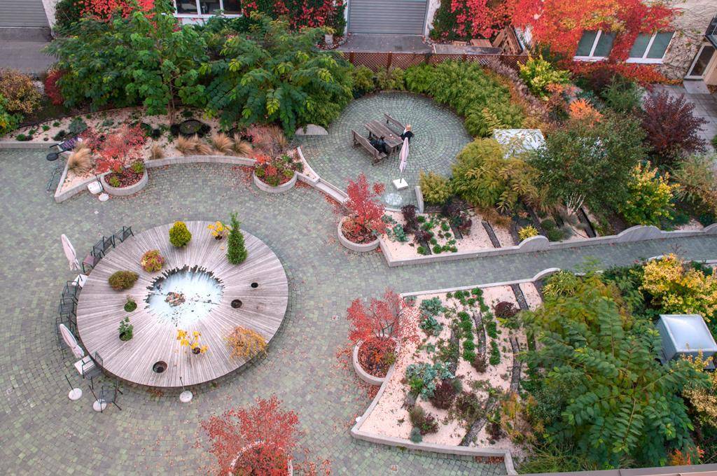 Attraktiver Innenhofgarten mit vielfältiger Bepflanzung, Sitzgelegenheiten und herbstlicher Färbung.