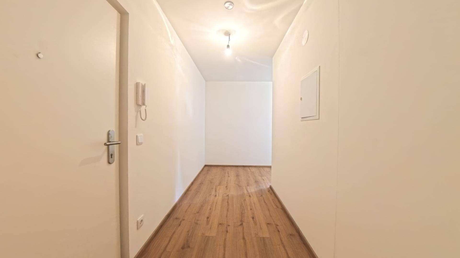Heller Flur mit Laminatboden und Gegensprechanlage am Eingangsbereich der Wohnung.