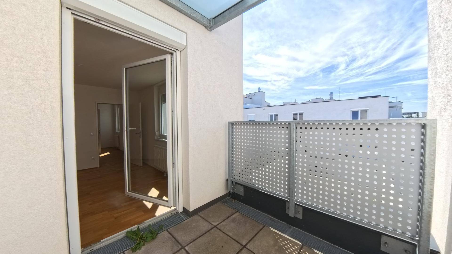 Blick von der Terrasse in den hellen Innenraum mit Holzparkettboden.