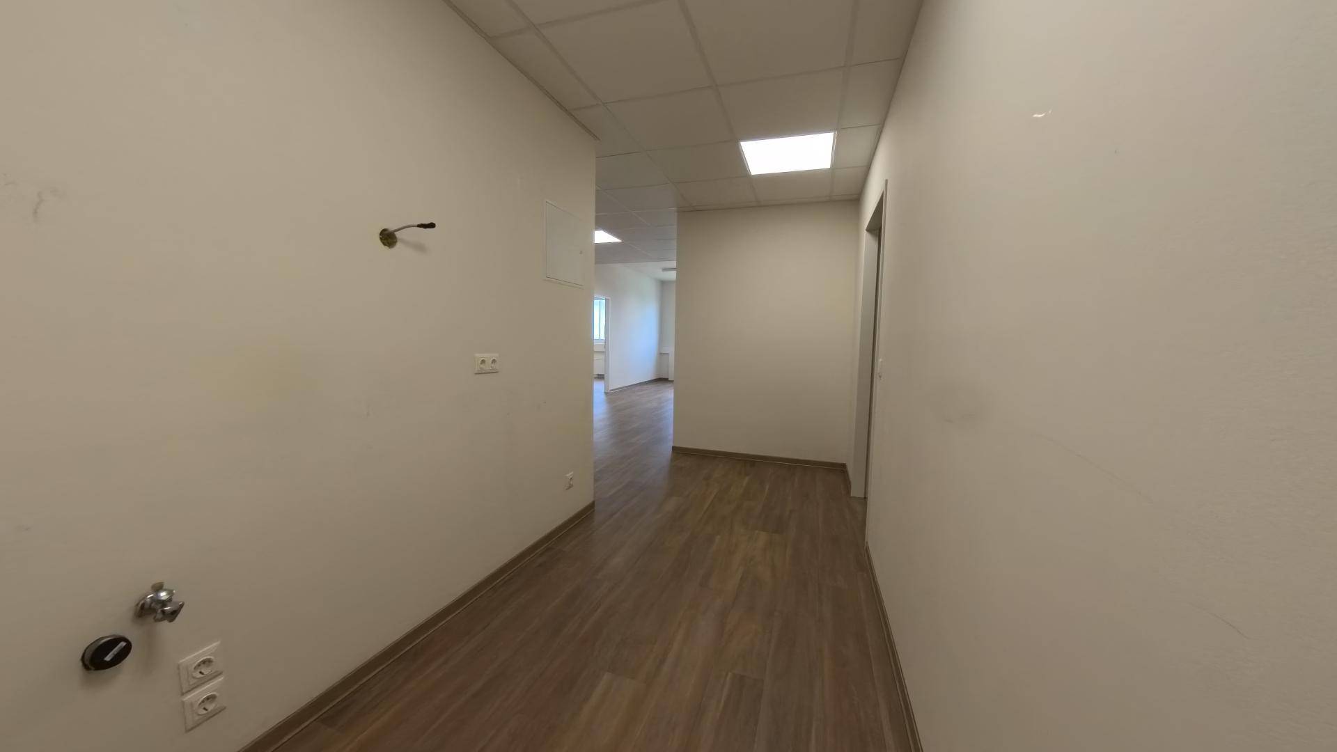 Flur mit Laminatboden und sichtbaren Anschlüssen an der Wand, der zu weiteren Räumen führt.