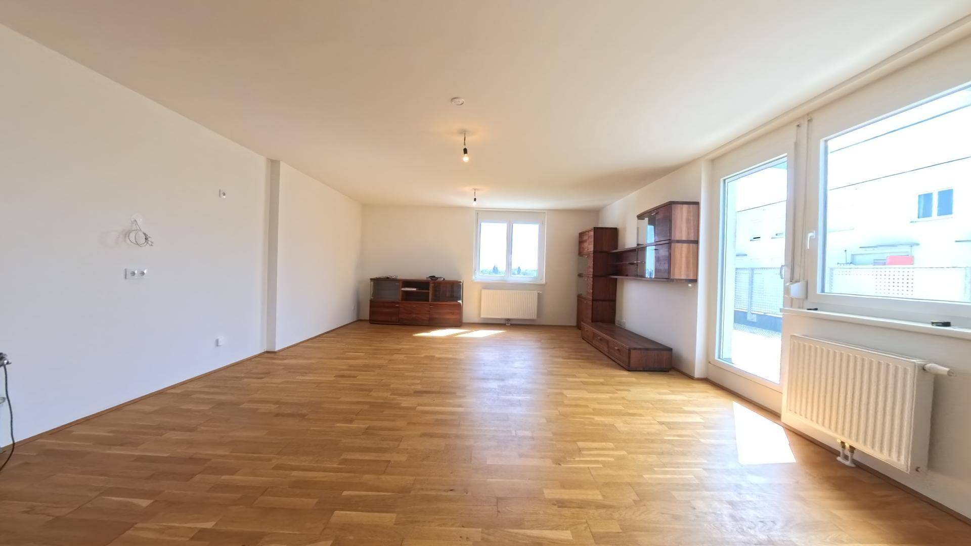 Helles Wohnzimmer mit mehreren Fenstern, die den Raum mit natürlichem Licht durchfluten.