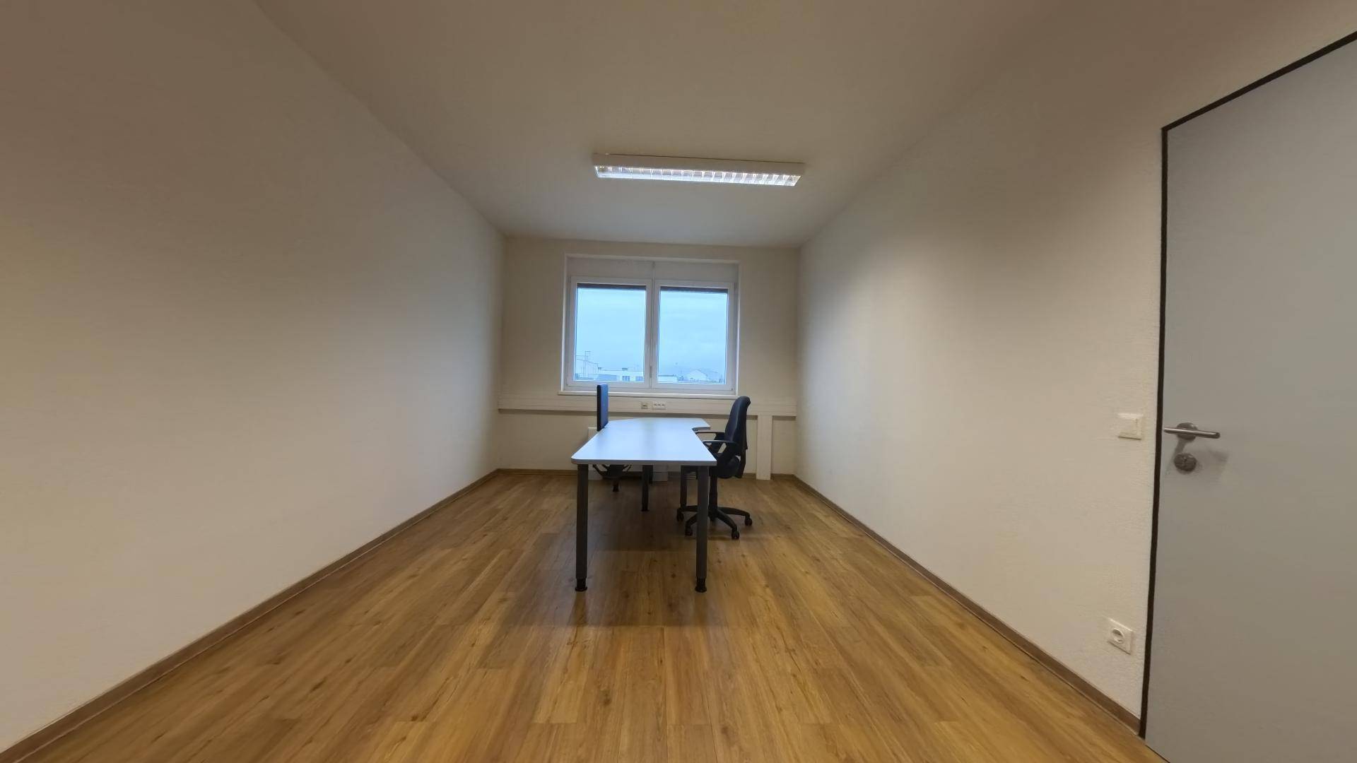 Langes Büro mit Holzfußboden, einem Schreibtisch und Blick aus dem Fenster, bietet viel Platz.