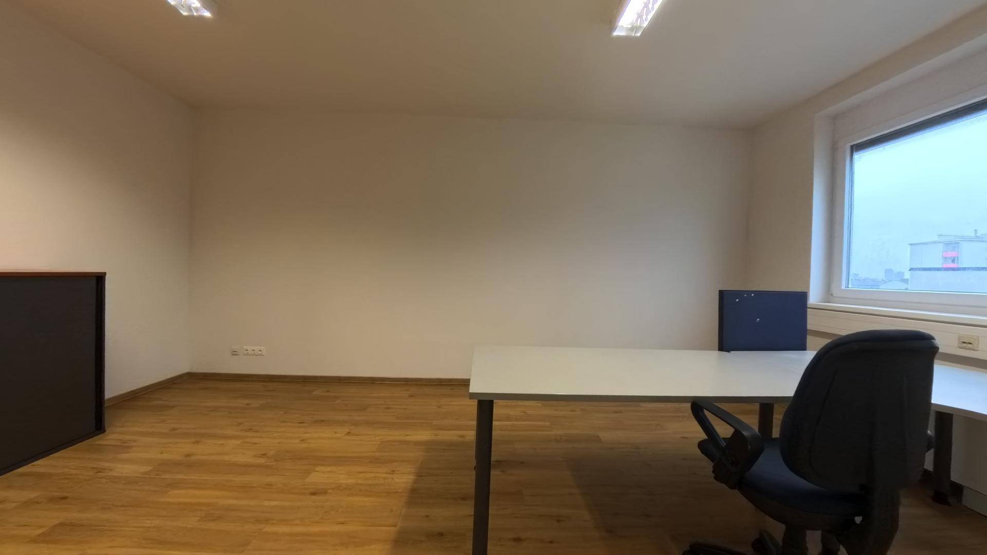 Helles Büro mit Holzfußboden, Schreibtisch und einer breiten Fensterbank, die viel Licht hereinlässt.